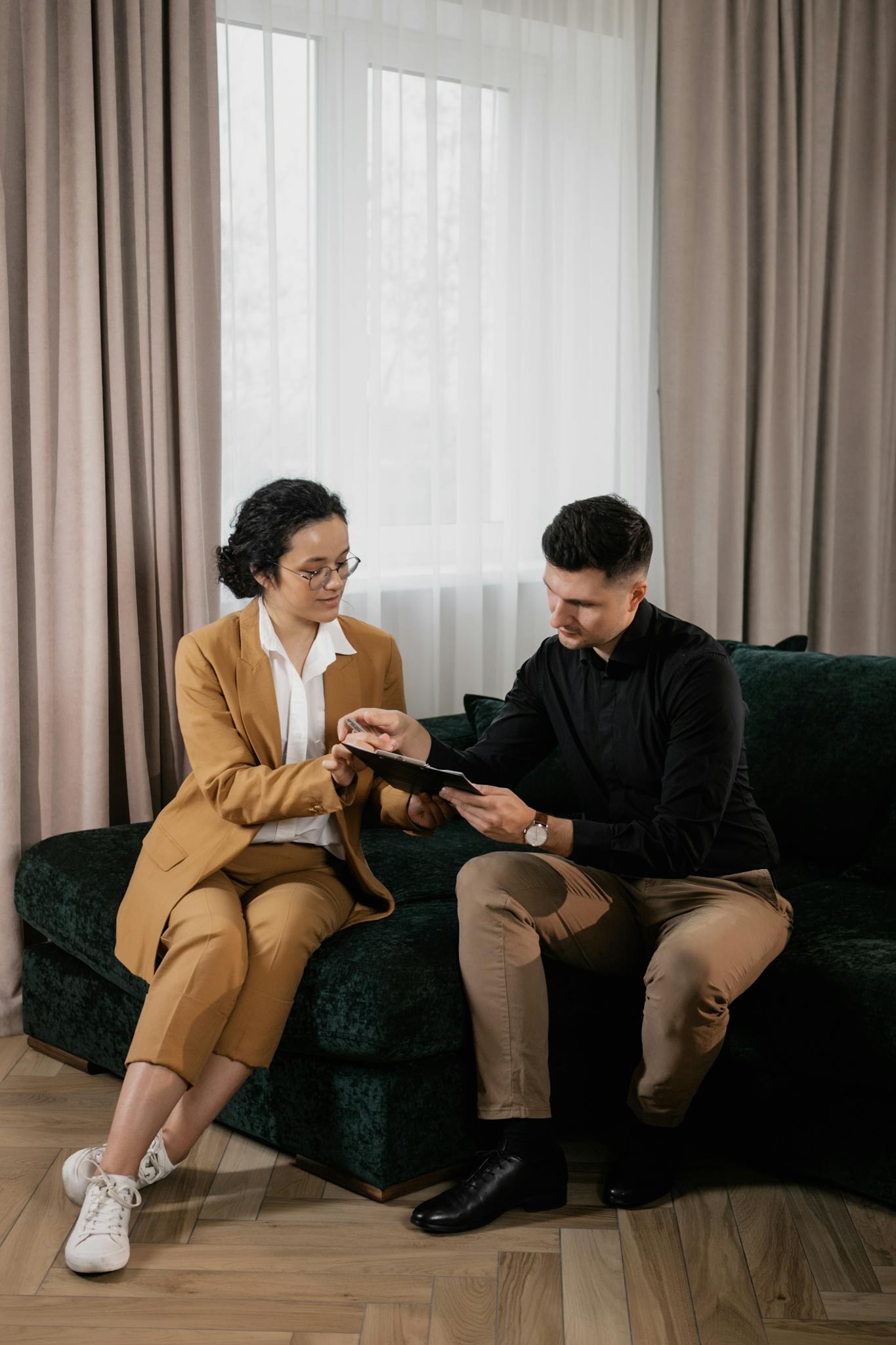 A real estate agent consults with a client, discussing documents in a cozy living room.